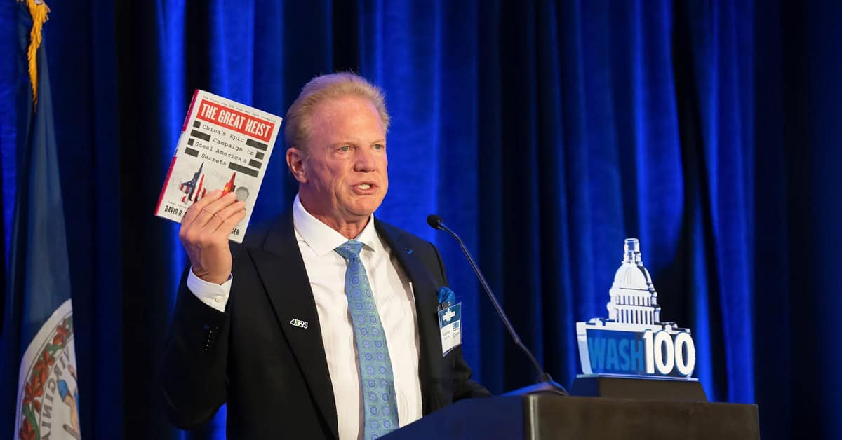 jim-garrettson-executive-mosaic-the-great-heist-david-shedd-china Jim Garrettson holding The Great Heist book. The Executive Mosaic CEO displayed David Shedd's book on China's IP theft at the 2026 Intel Summit.